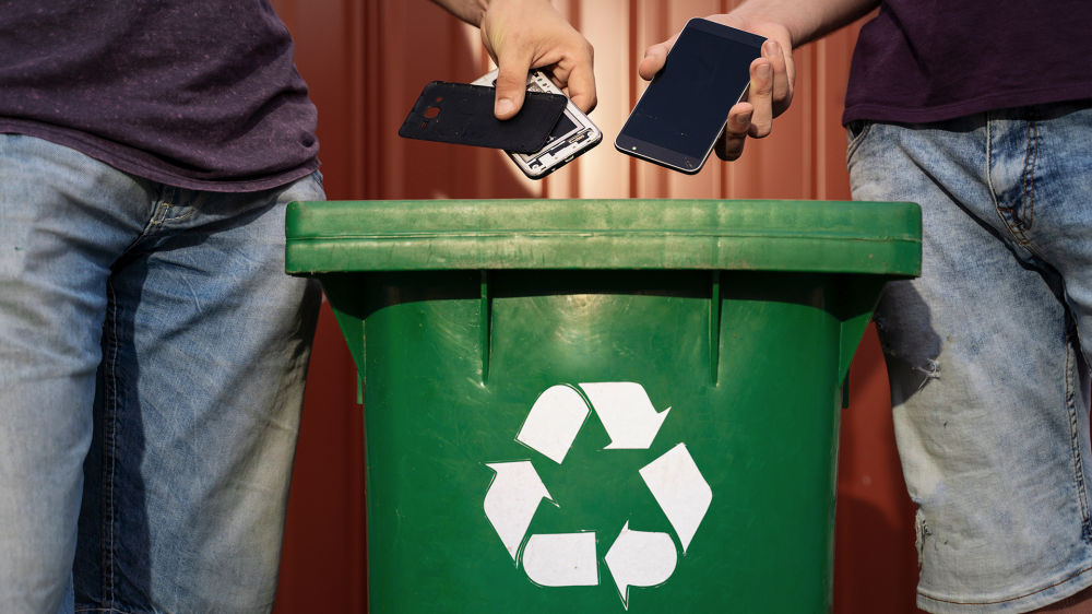 People placing phones in a recycling bin.